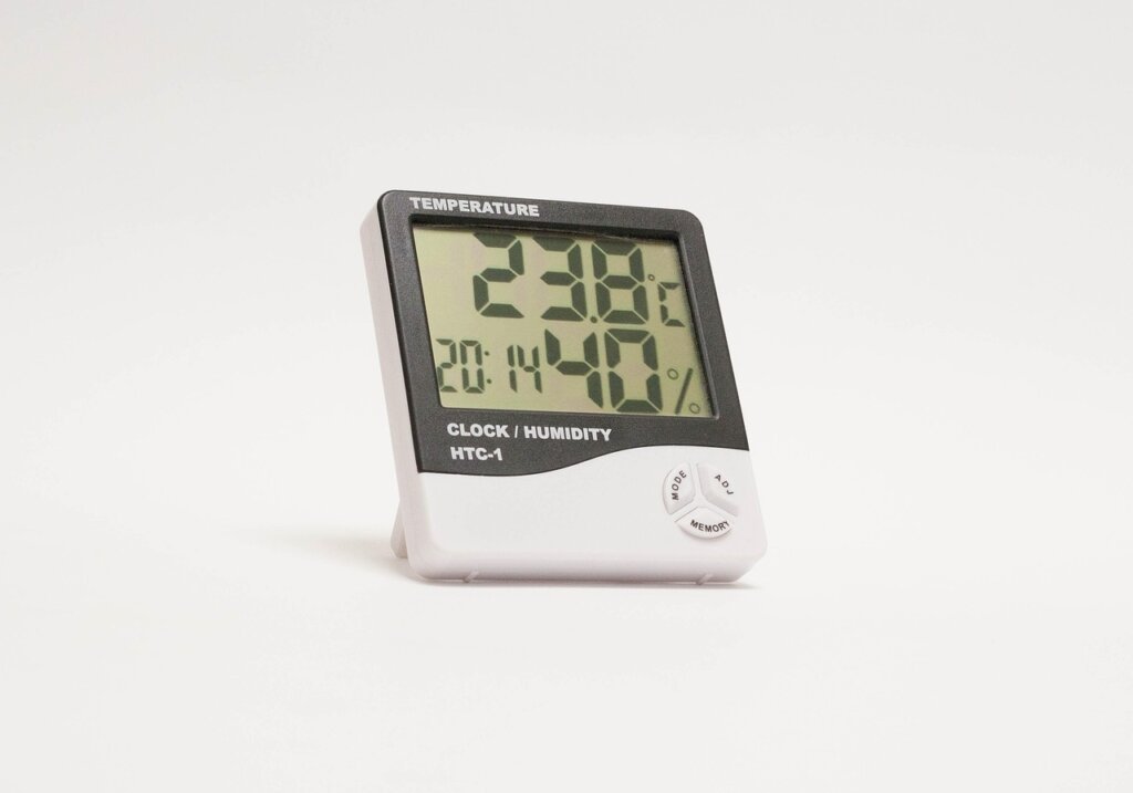 digital hygrometer showing humidity level 55 percent on a wooden shelf indoors