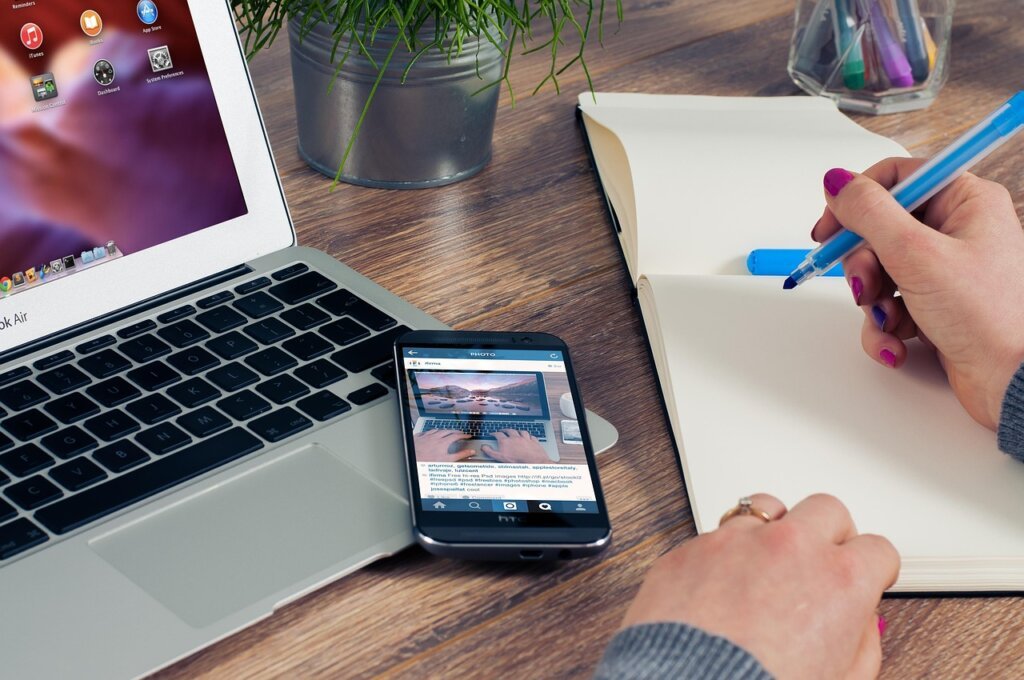 small business owner checking finances on smartphone and laptop
