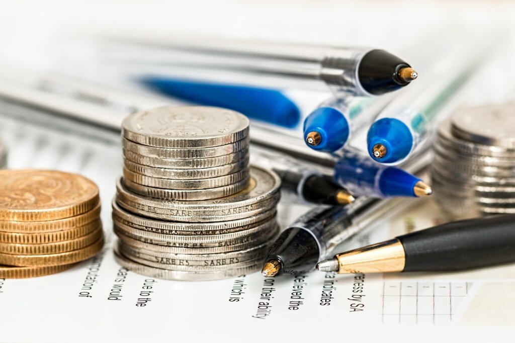 savings amount calculation on notebook with pen and coin stack