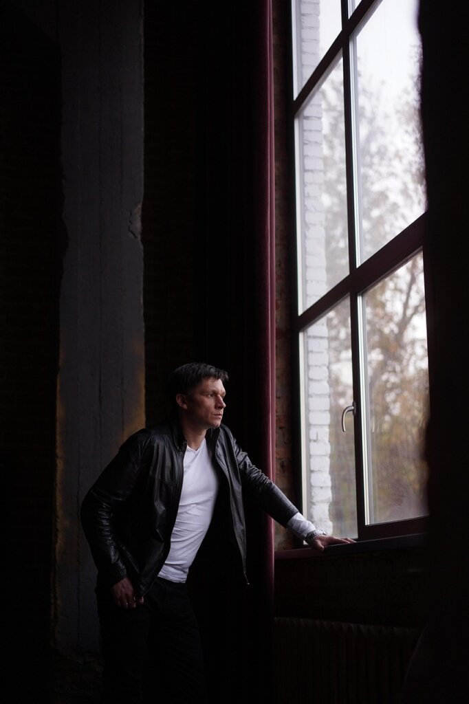 Hopeful middle-aged Korean man looking out window with soft morning light