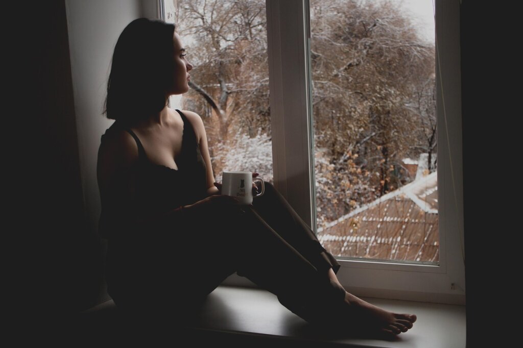 elderly Korean woman looking out window with caregiver beside her