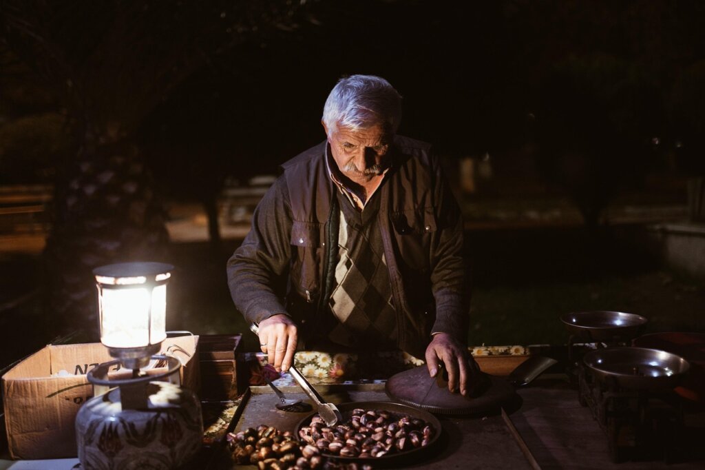 elderly Korean man using computer at small business market stall selling products